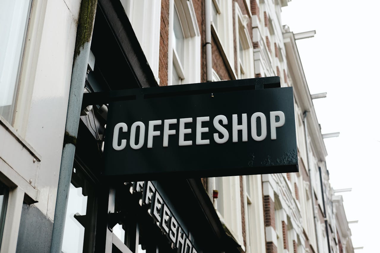 Coffeeshop sign on a classic Amsterdam street, highlighting Dutch architecture.