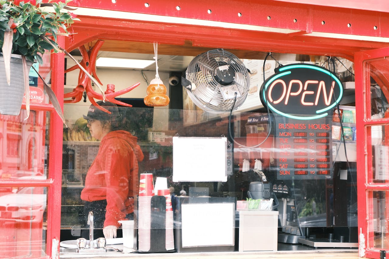 Vibrant red café shopfront with neon open sign, showcasing a bustling interior.