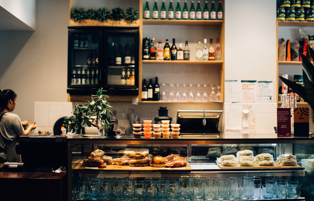 Warm café setting with sandwiches and drinks on display at the counter.